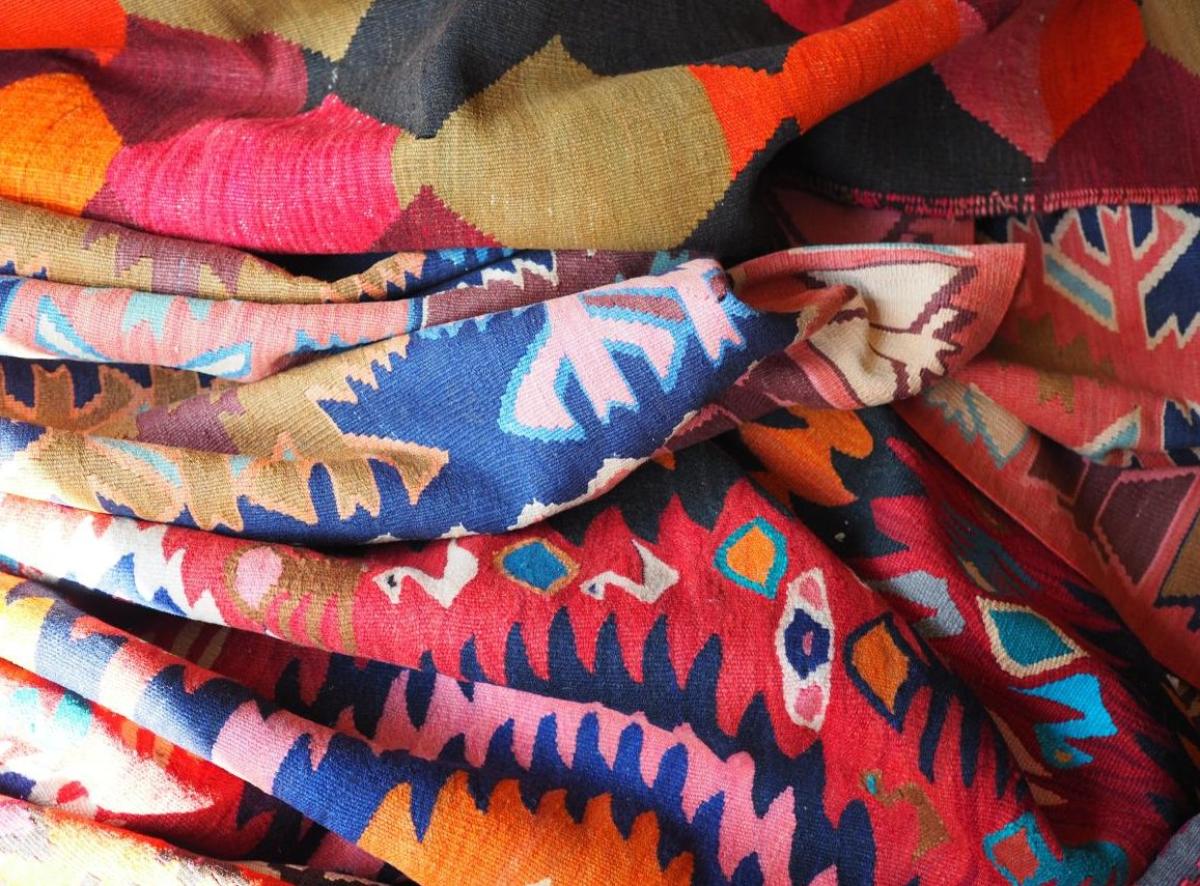 Prise de vue détaillée d'un tapis kilim plié dans des tons de bleu, rouge et orange avec un motif gé